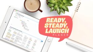Der Ready, Steady, Launchplaner auf einem Tablet, daneben Kaffee, Pflanze und Notizblock
