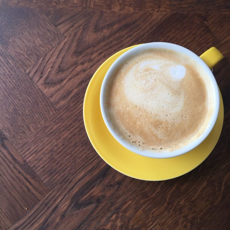 Milchkaffee in einer gelben Tasse auf einem Holztisch